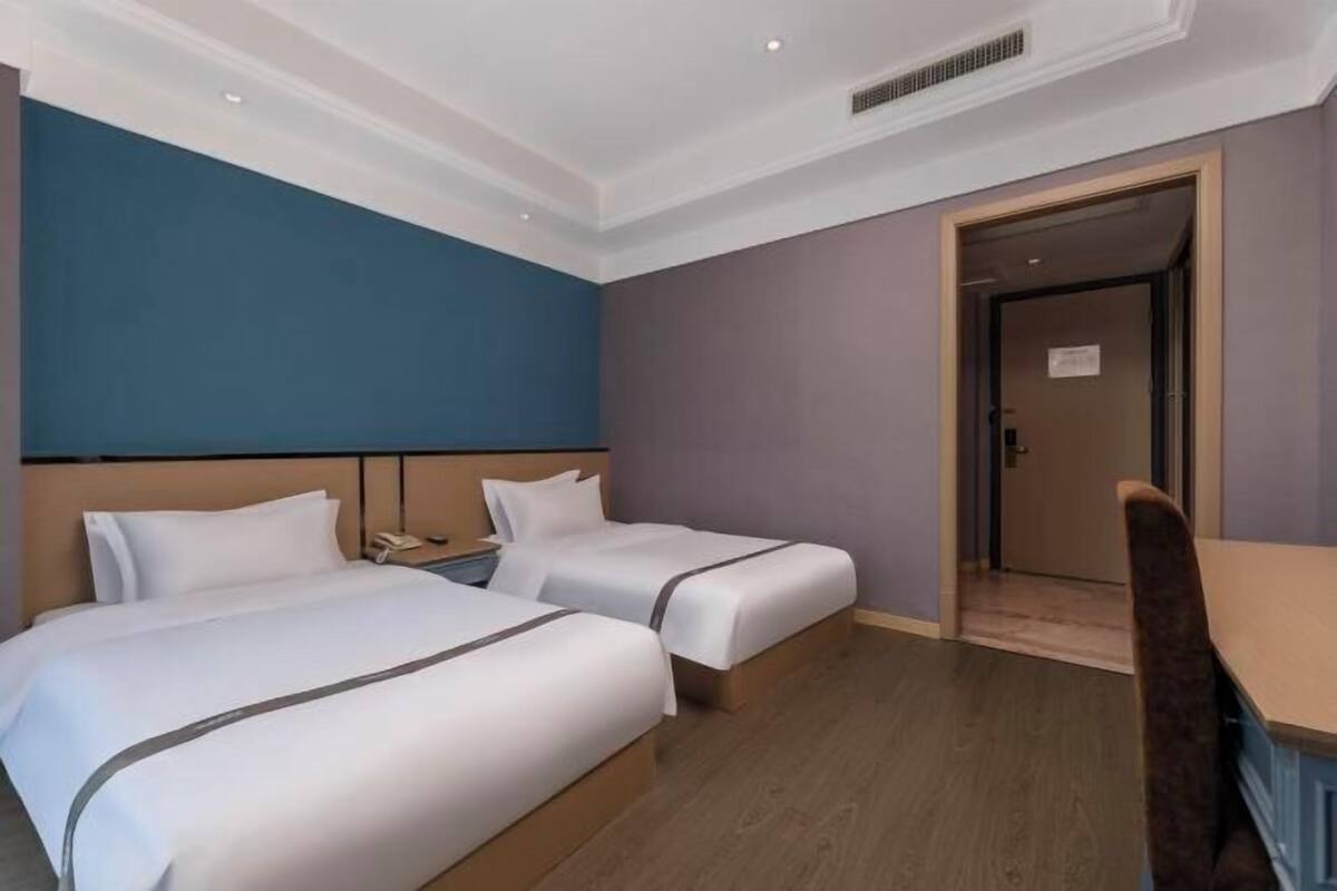 A hotel room with two beds, a desk, and a chair.