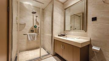 A modern bathroom with a glass-enclosed shower, a large mirror, and a wooden vanity.