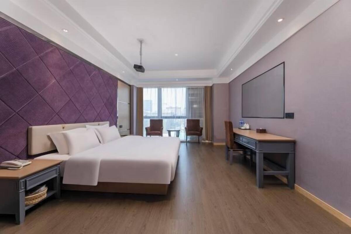 A modern hotel room with a large bed, a desk, and a television.