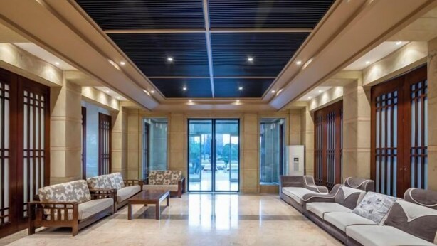 Eine großzügige Lobby mit hoher Decke, großen Fenstern und einer Sitzecke mit Sofas und Sesseln.