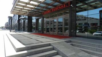 A building with a glass facade, a red carpet entrance, and a set of stairs leading to the entrance.