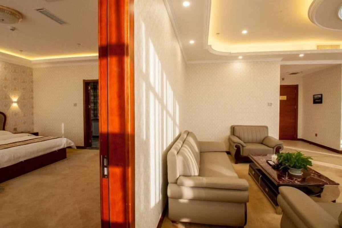 Una habitación de hotel con cama, sofá, sillón y mesa de centro.
