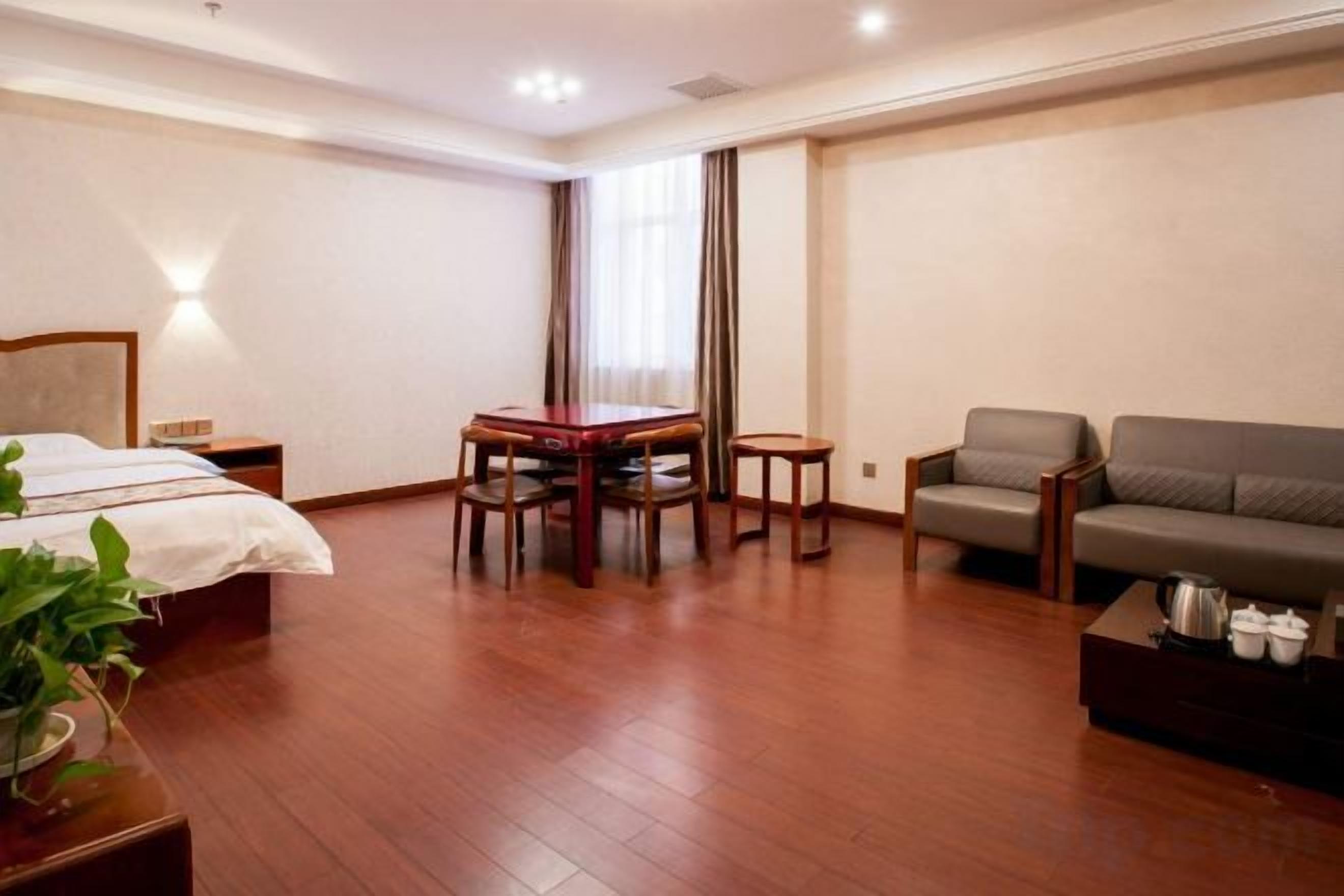 Una habitación de hotel con cama, una mesa de comedor con sillas, un sofá y una mesita con tetera.