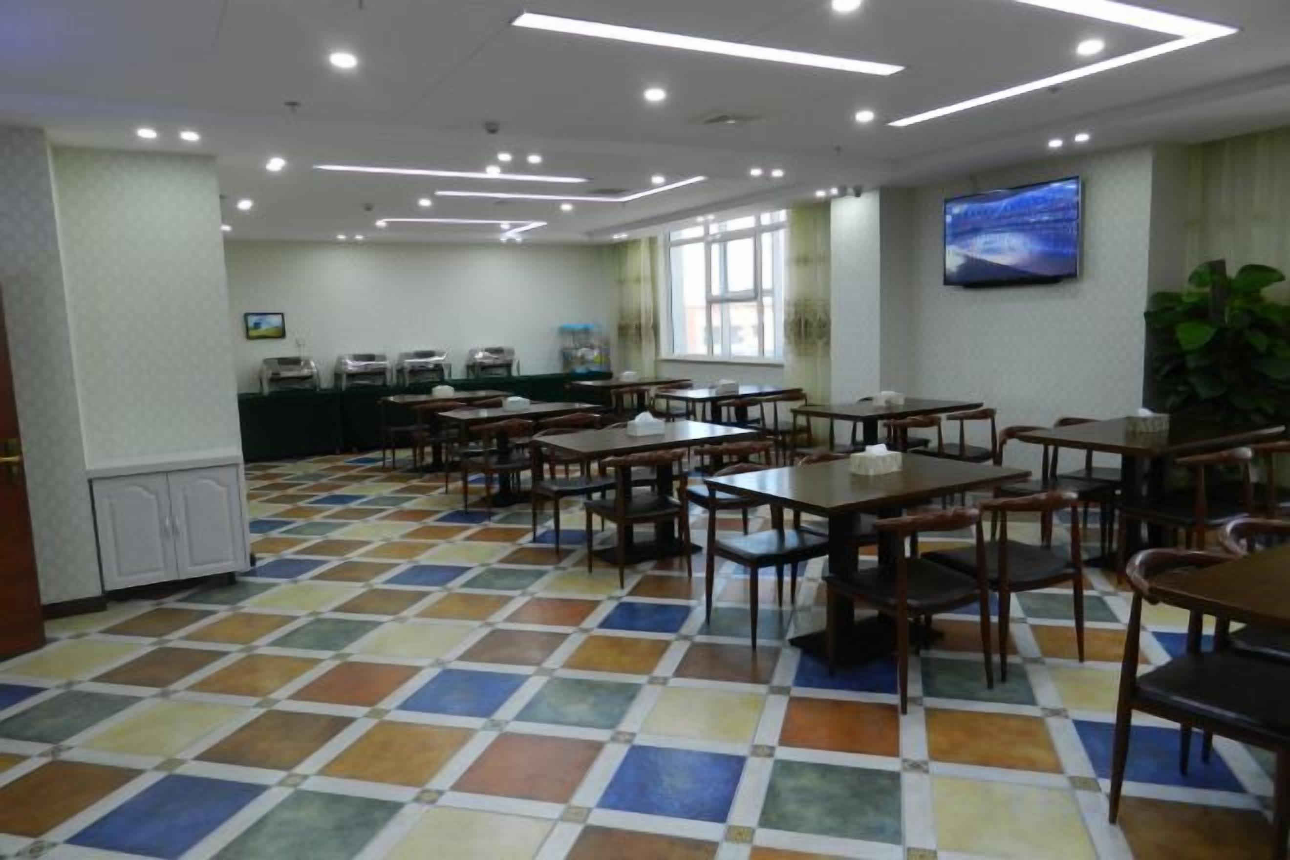A dining area with tables and chairs, a television on the wall, and a patterned floor.