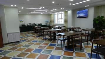 A dining area with tables and chairs, a television on the wall, and a patterned floor.