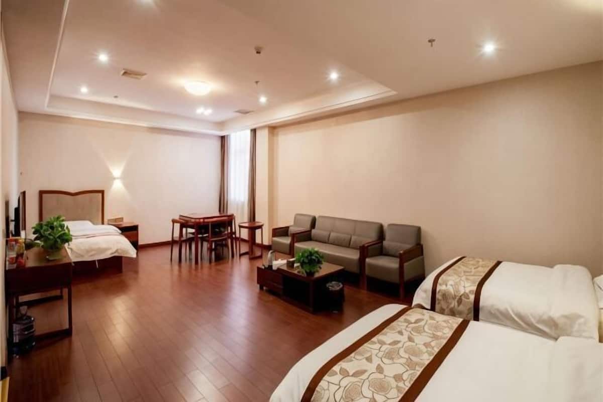 Una habitación de hotel con una cama, un sofá, una mesa de centro, un escritorio y una silla.