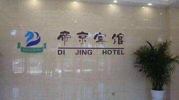 Entrada de un hotel con un letrero que dice 'DI JING HOTEL' y un logotipo encima.