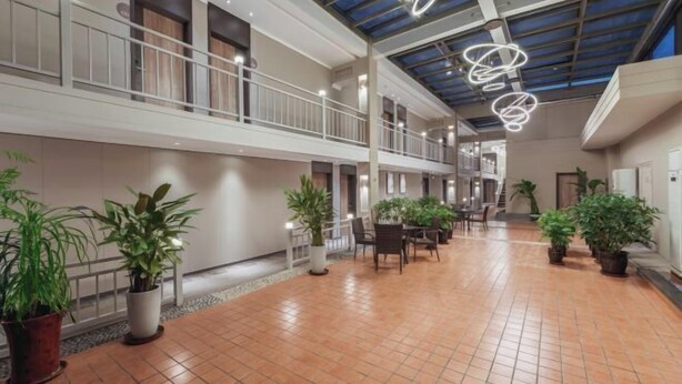 A spacious indoor area with a tiled floor, potted plants, a balcony with a railing, and a ceiling with a skylight and hanging light fixtures. - Homeinn · neo (Taiyuan Railway Station Shuangta East Street) (Taiyuan)