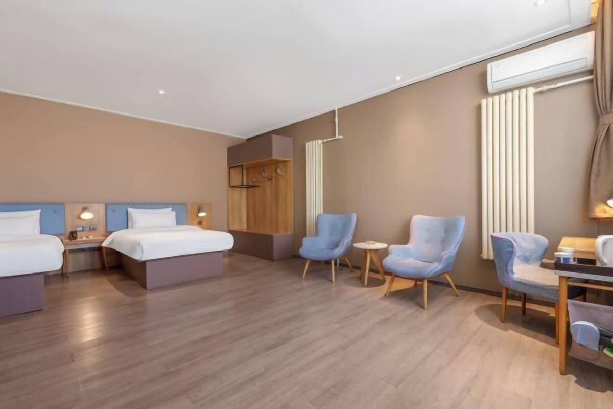 A hotel room with two beds, a desk, a chair, and a small table.