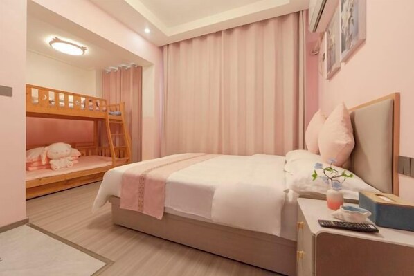Un dormitorio con una cama litera, una mesita de noche con un control remoto, una lámpara y una ventana con cortinas.