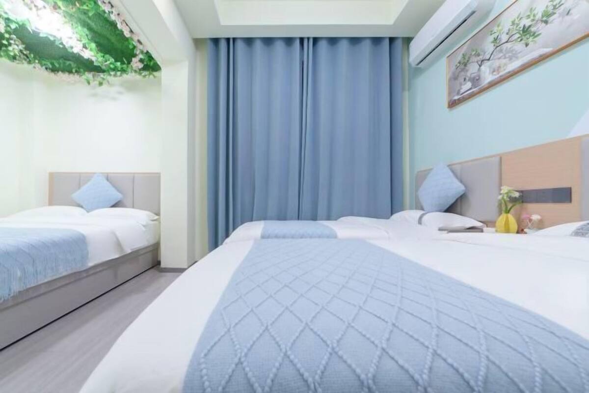 Habitación de hotel con dos camas, un ventanal con cortinas, un aire acondicionado instalado en la pared y un cuadro.