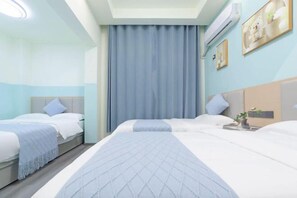 Habitación de hotel con dos camas, un ventanal con cortinas, un aire acondicionado de pared y una pequeña mesa con una planta.