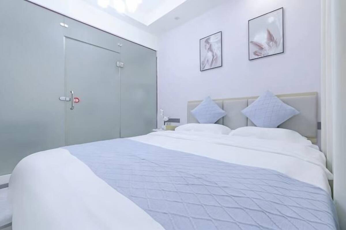 Un dormitorio con cama, dos almohadas, una mesita de noche, un armario y dos cuadros en la pared.