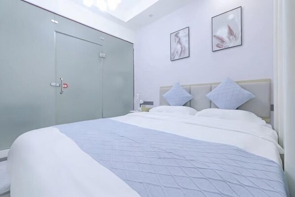 Un dormitorio con cama, dos almohadas, una mesita de noche, un armario y dos cuadros en la pared.