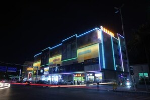 A multi-story building with illuminated signage and storefronts at night. - jinlouerhotle (Shenzhen)