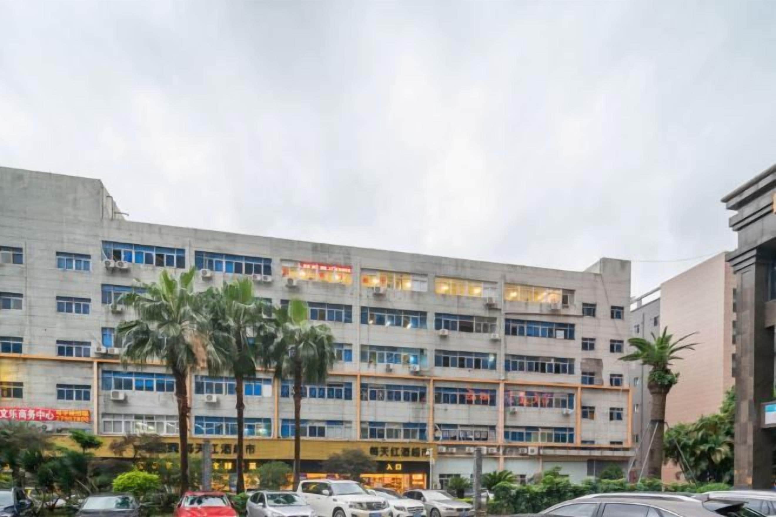 A multi-story building with a flat facade, several windows, and a parking lot with cars.