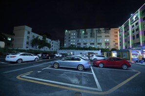 A parking lot with cars and a building with illuminated windows in the background. - jinlouerhotle (Shenzhen)