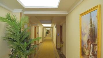 A hotel hallway with a skylight, a carpeted floor, and a painting on the wall.