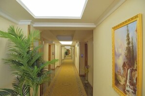 A hotel hallway with a skylight, a carpeted floor, and a painting on the wall. - jinlouerhotle (Shenzhen)