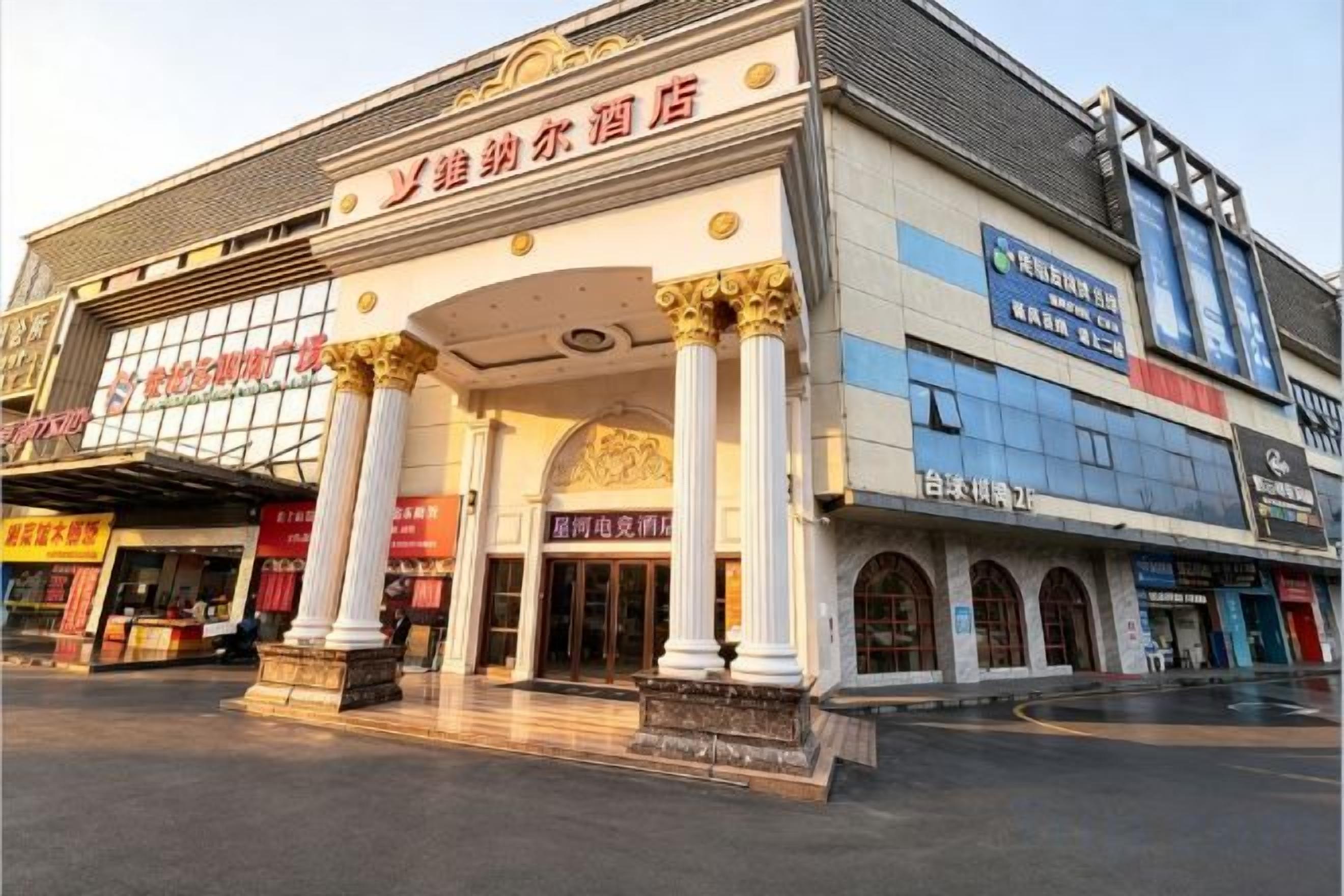 A building with a large entrance, columns, and multiple signs.
