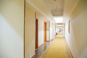 A hotel corridor with doors on both sides, a patterned carpet, and framed pictures on the walls. - Vernal Hotel (Shenzhen Shiyan Shilongzi Branch) (Shenzhen)
