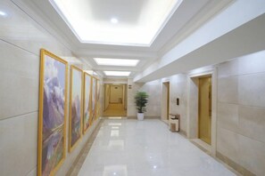 A hallway with a ceiling light, a potted plant, and a door.