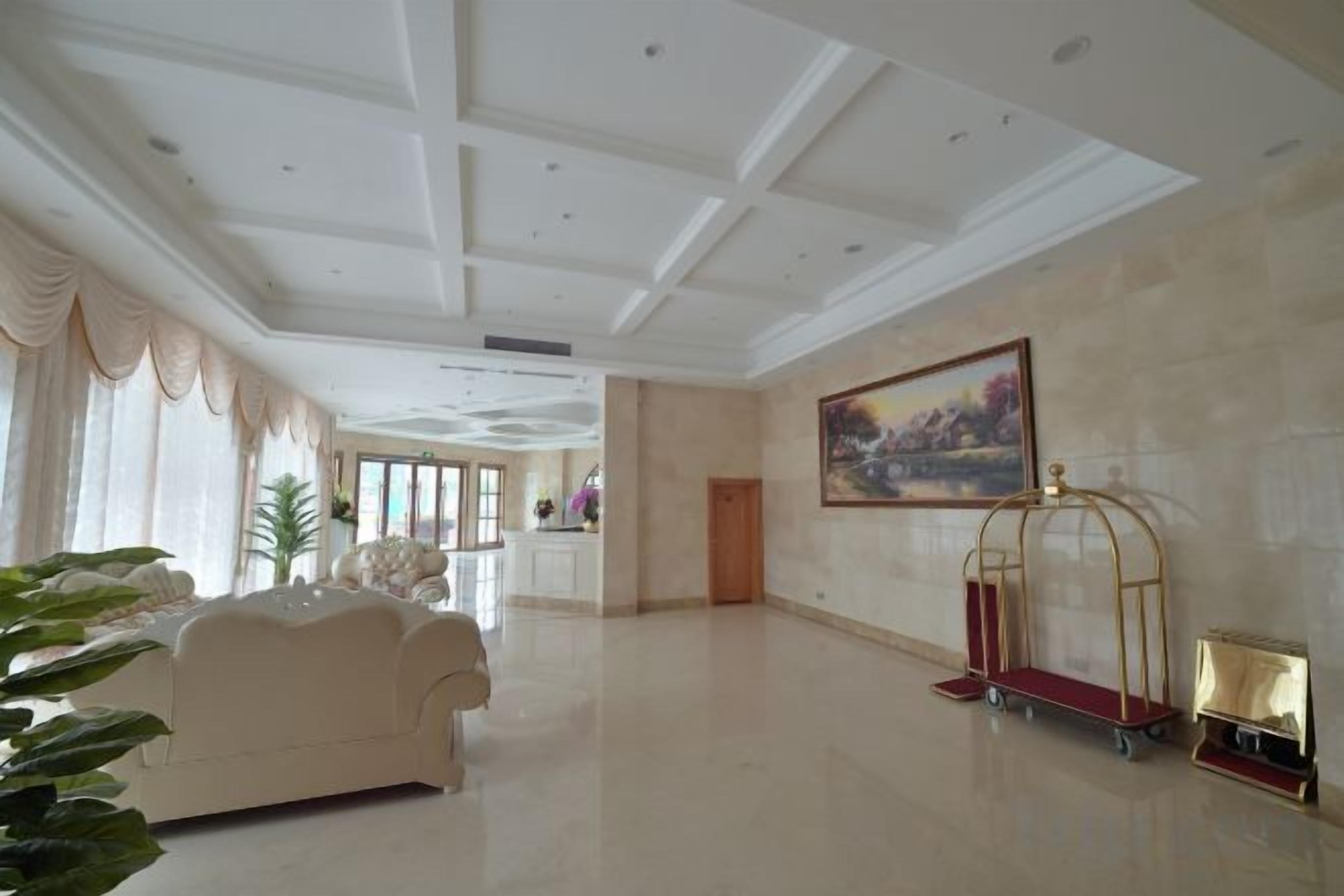 A spacious lobby with a high ceiling, a seating area, and a painting on the wall.