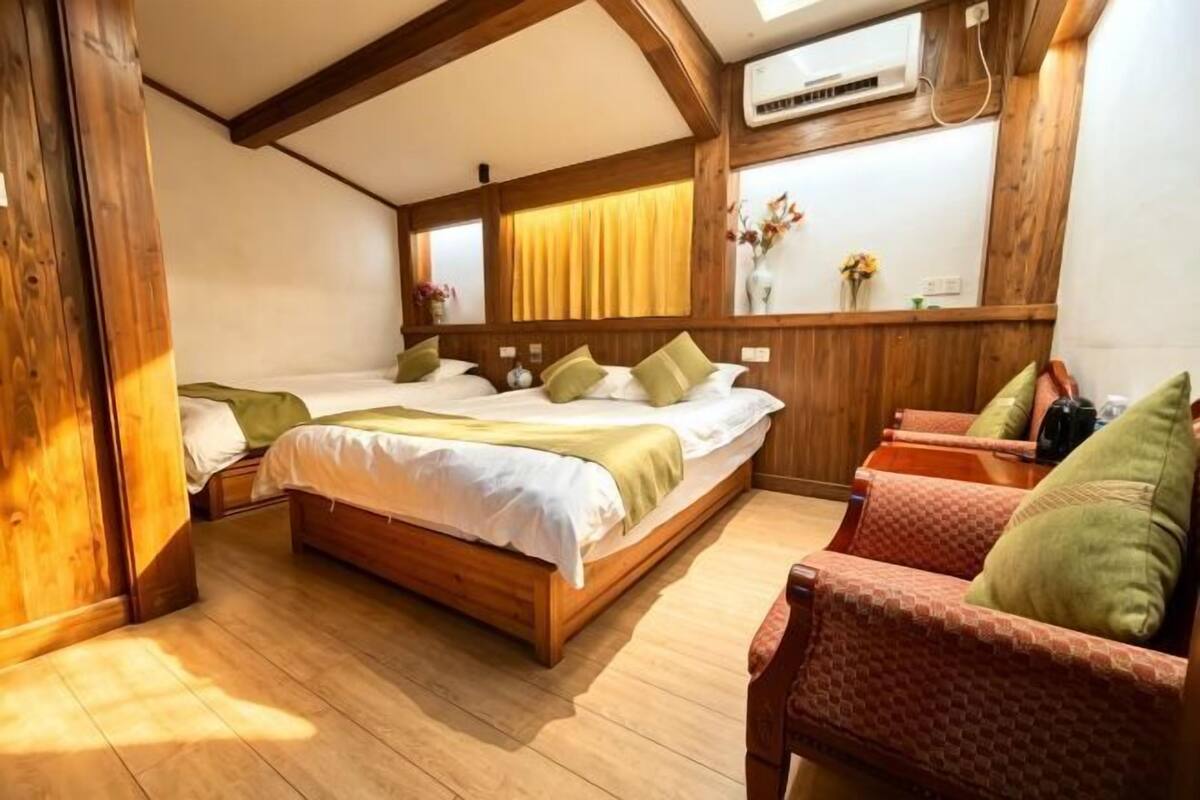 Une pièce avec un lit en bois, une chaise et une fenêtre avec des rideaux.