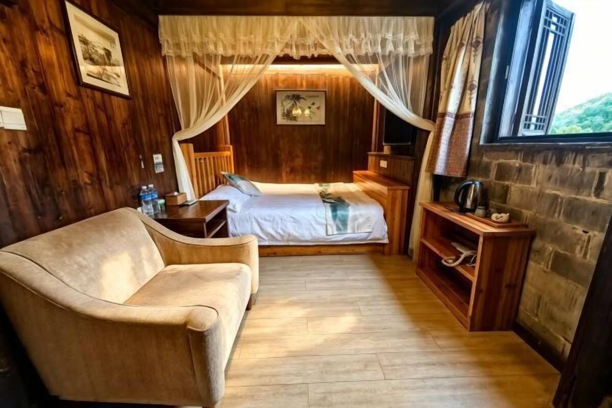 Une pièce en bois avec un lit, un canapé, une télévision et une fenêtre avec des rideaux.
