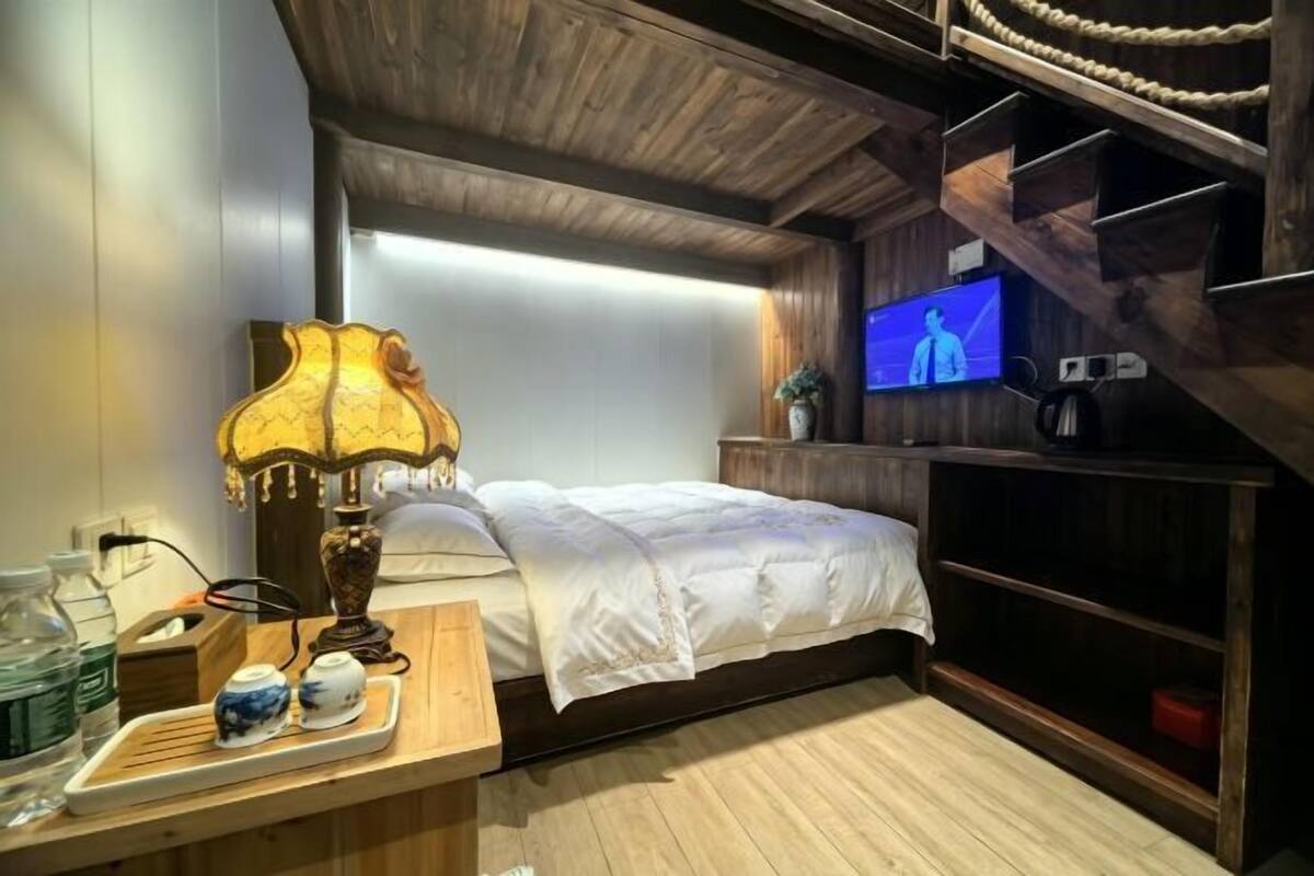 Une chambre à coucher avec un lit, une télévision, un plafond en bois et une table de chevet avec une lampe et des théières.