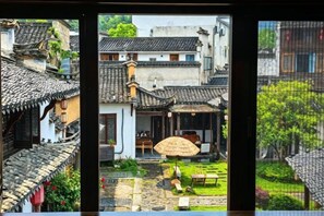 Une cour traditionnelle avec des toits en tuiles, un parasol en chaume et un chemin pavé de pierres.