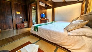 A wooden-paneled room with a bed, a television, and a small table with a water bottle.