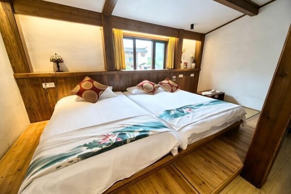 Una cama doble con ropa de cama floral, cabecera de madera y una ventana con cortinas.