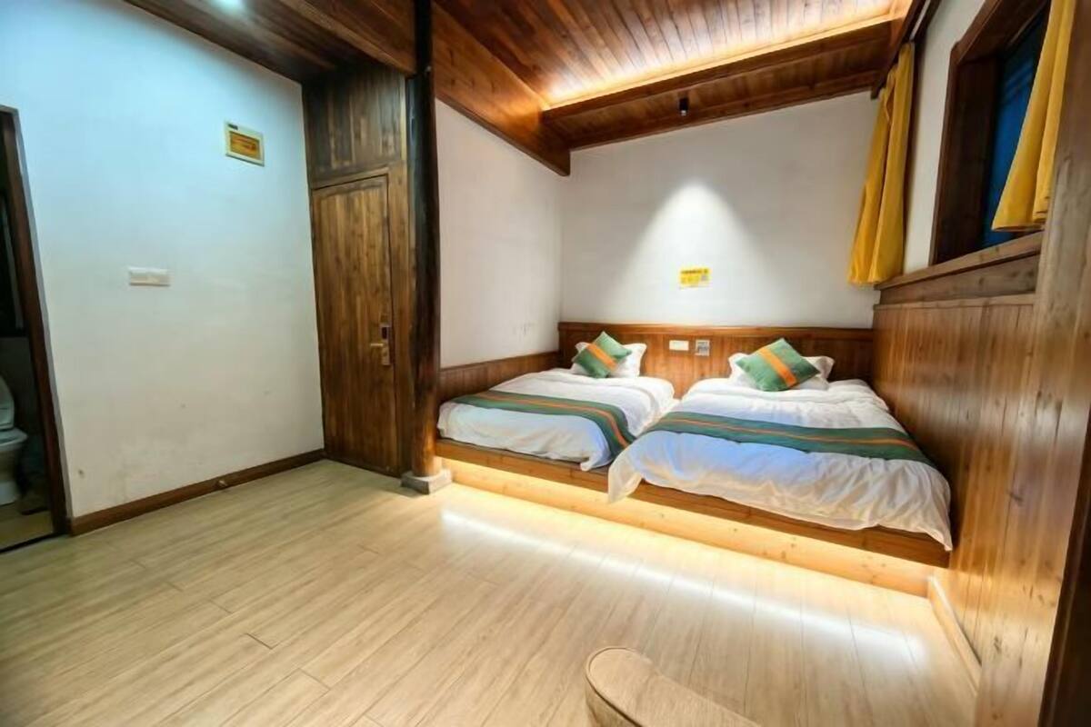 Une chambre avec deux lits, un plancher en bois et un plafond en bois.