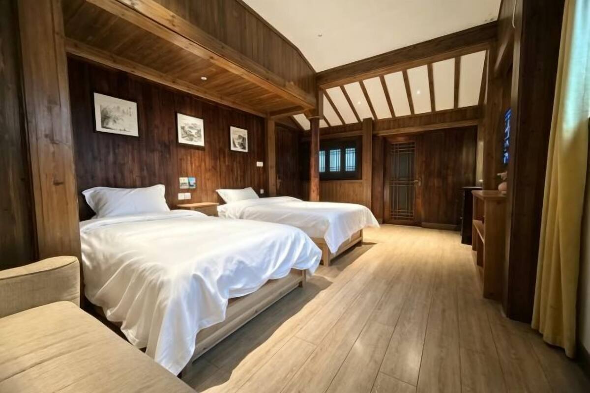 Une pièce en bois avec deux lits, un plancher en bois et une porte.