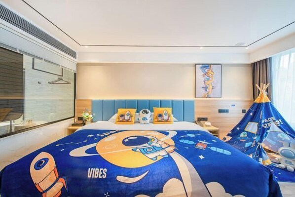 A hotel room with a bed featuring a space-themed bedspread, a blue headboard, a wall-mounted artwork, and a teepee-style tent with space-themed decorations. - BIJIU HOTEL (Foshan)