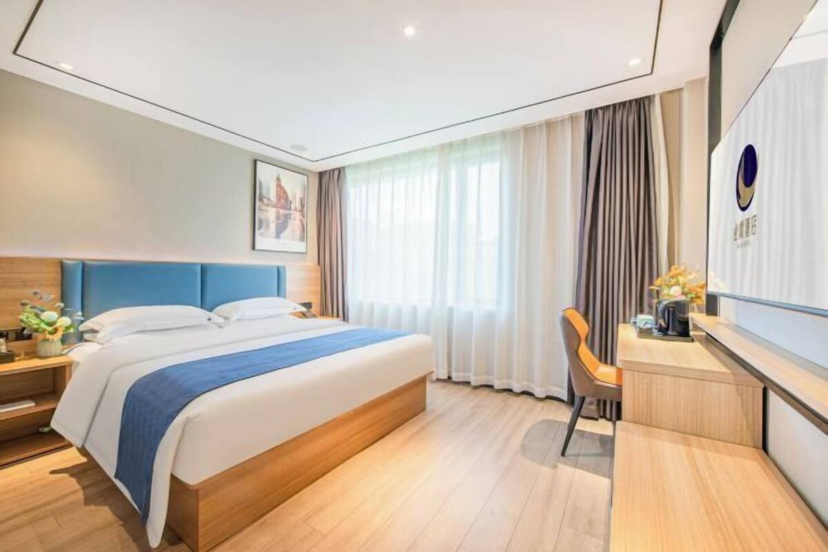 A modern hotel room with a large bed, a desk, and a chair.