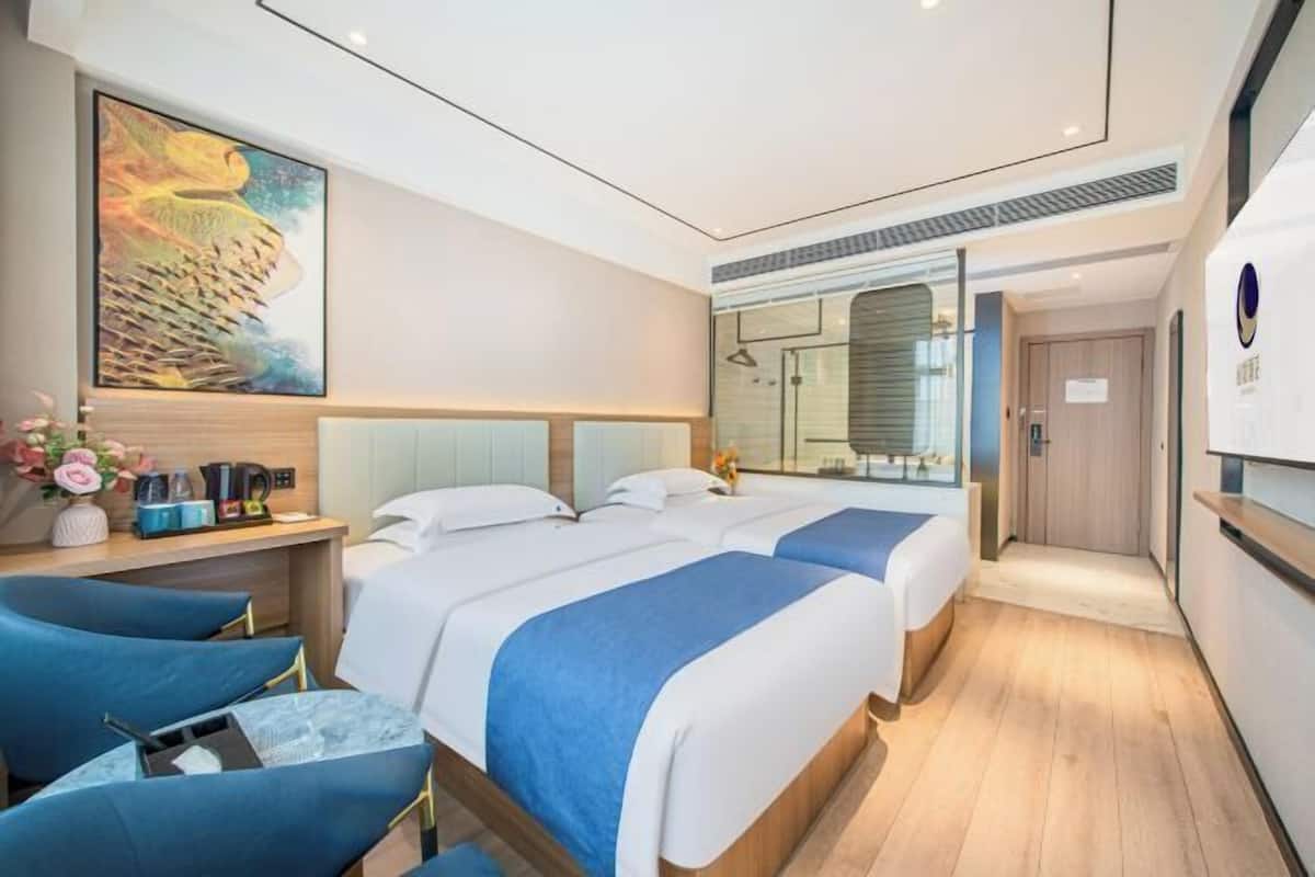 A modern hotel room with a large bed, a desk, and a seating area.