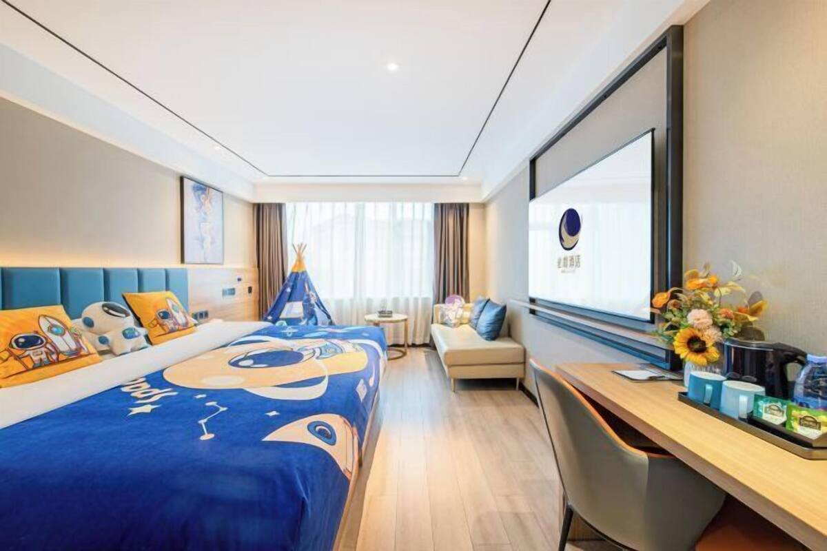 A hotel room with a bed, a desk, and a window.