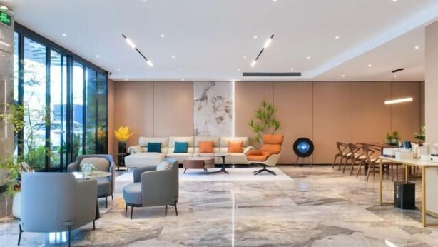 A modern hotel lobby with a seating area, a dining table, and a large window. - BIJIU HOTEL (Foshan)