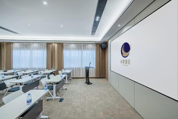 Un salón de conferencias con varias mesas, un atril y una pantalla grande en la pared.