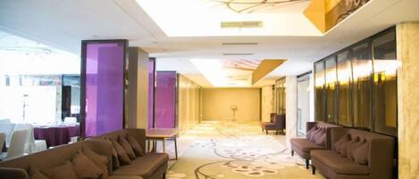 A hotel lobby with a reception desk, two sofas, and a patterned carpet.