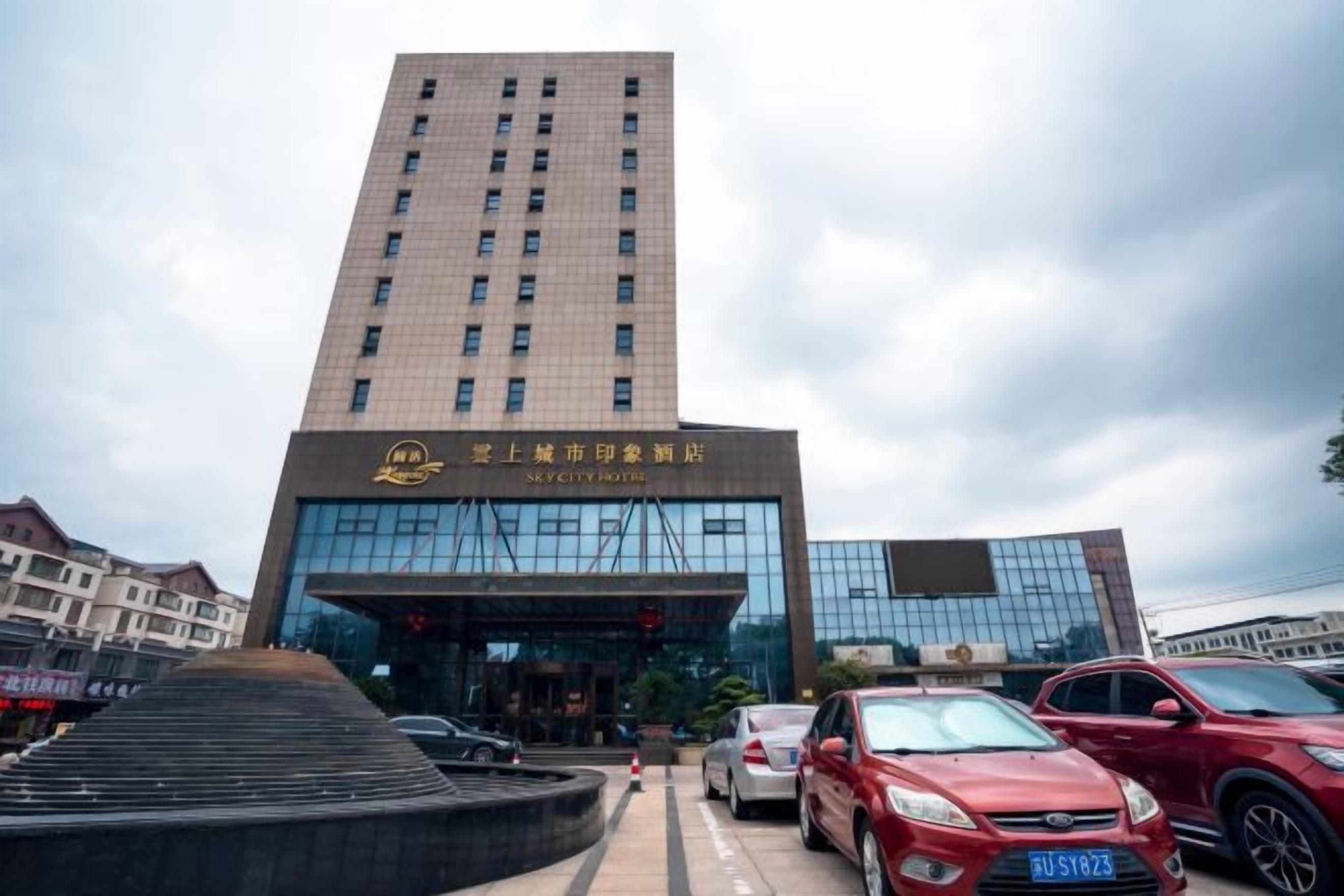 Un edificio a più piani con una facciata moderna, un ingresso ben visibile e un'area di parcheggio con auto.