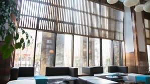 Un intérieur moderne avec de grandes fenêtres, des coins salon et des luminaires suspendus.