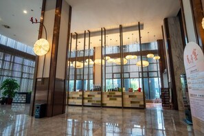 A spacious lobby with a modern design, featuring a reception desk, large windows, and hanging pendant lights. - Yunshang City Impress Hotel (Wuxi)