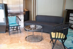 A room with a sofa, two chairs, a small round table, and a television. - Yunshang City Impress Hotel (Wuxi)