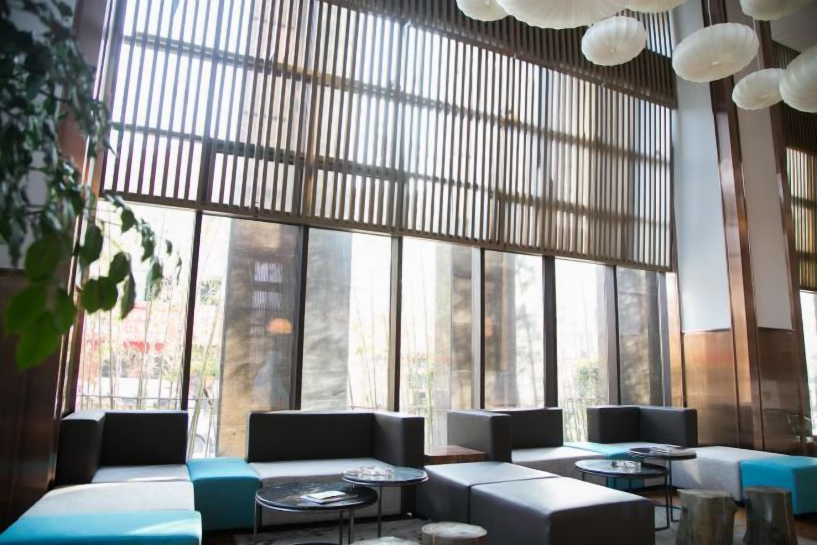 A modern interior with large windows, seating areas, and hanging light fixtures.