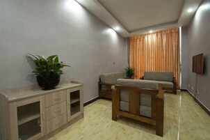 Una sala de estar con sofá, banco de madera, aparador y planta en maceta.