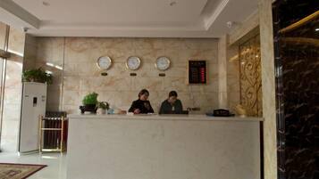 A reception desk with three clocks, a potted plant, and a digital display.