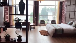 Una habitación de hotel moderna con una cama grande, un escritorio, una silla y vistas amplias a través de grandes ventanales.